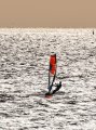 Mooie foto van Henk Slaa, foto tegen de ondergaande zon in genomen. Rood van het zeil zie je terug in het water voor zijn plank.